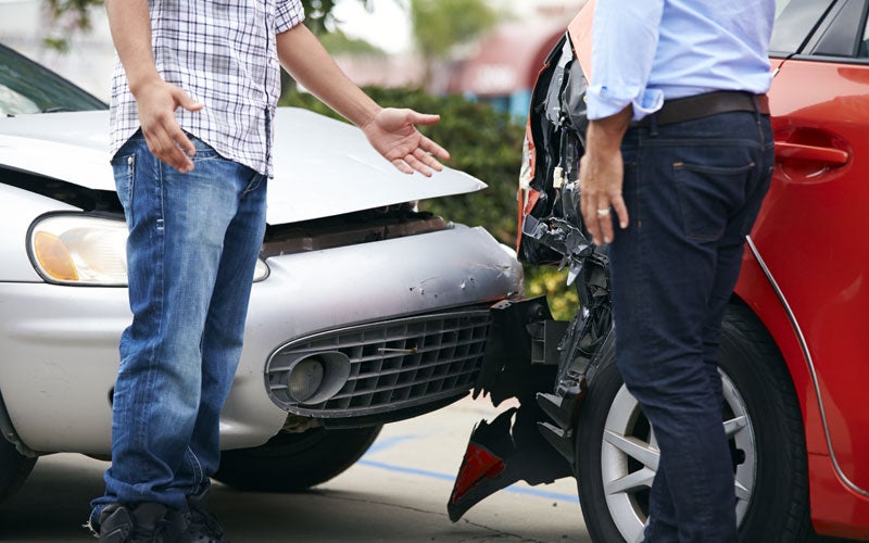 Two drivers inspecting damage after a fender-bender car accident.