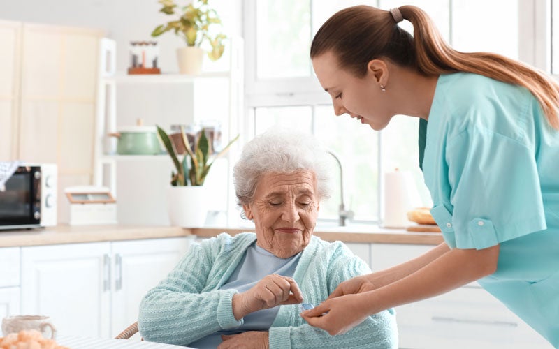 Caregiver assisting elderly woman with medication