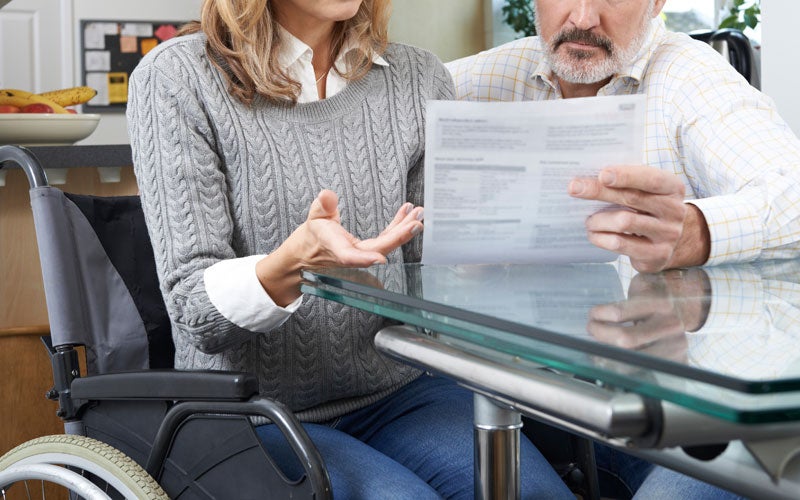 Woman in wheelchair discussing a document with a man