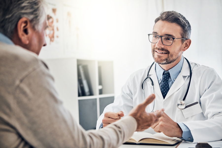 Male doctor talking with elderly patient in office.