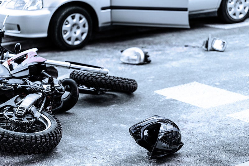 Motorcycle, helmet, and car debris after a road accident.