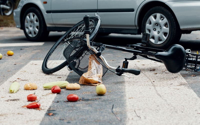 Bicycle and groceries scattered after accident with silver car