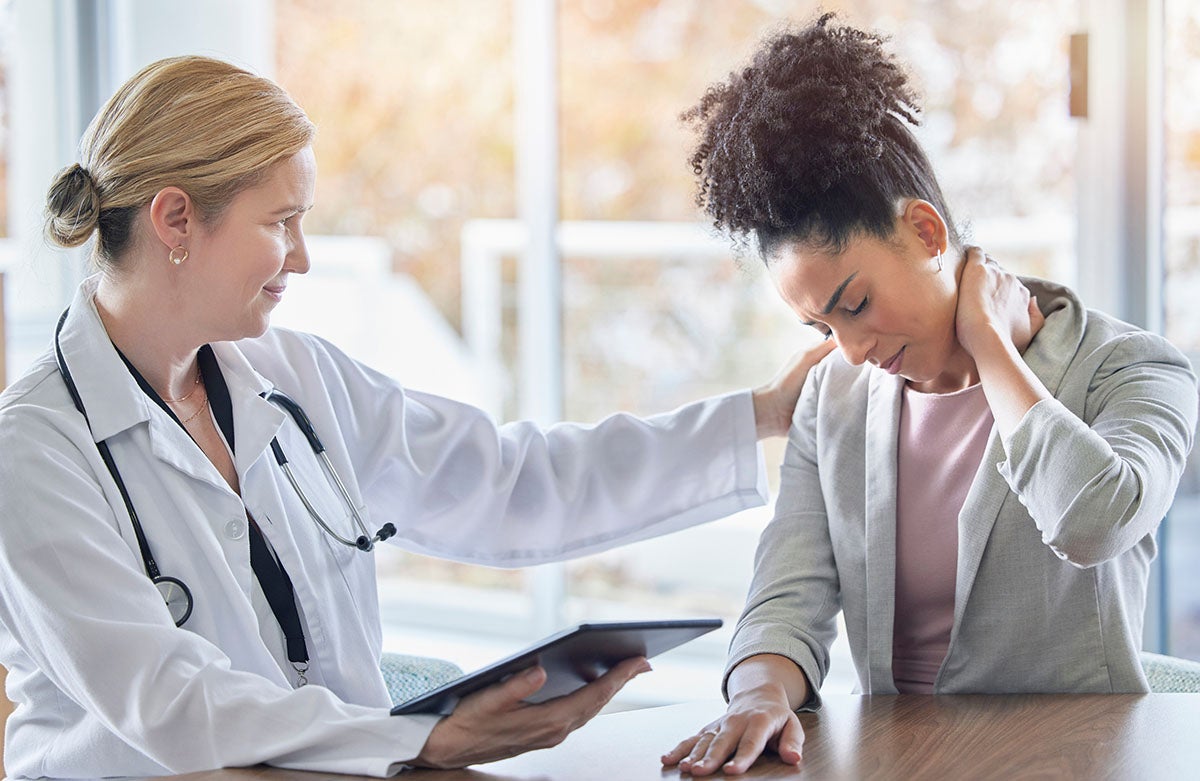 Female doctor comforting woman suffering from neck pain