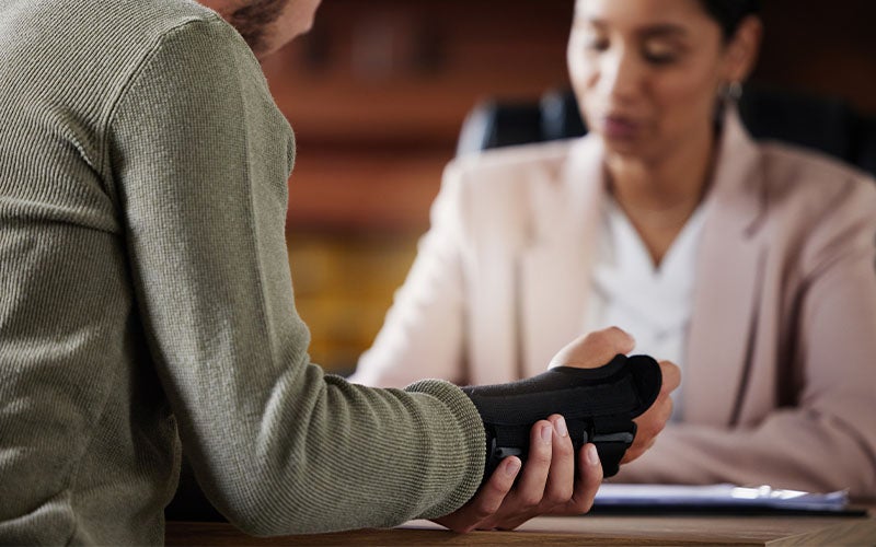 Man with hand brace talking to woman in an office.